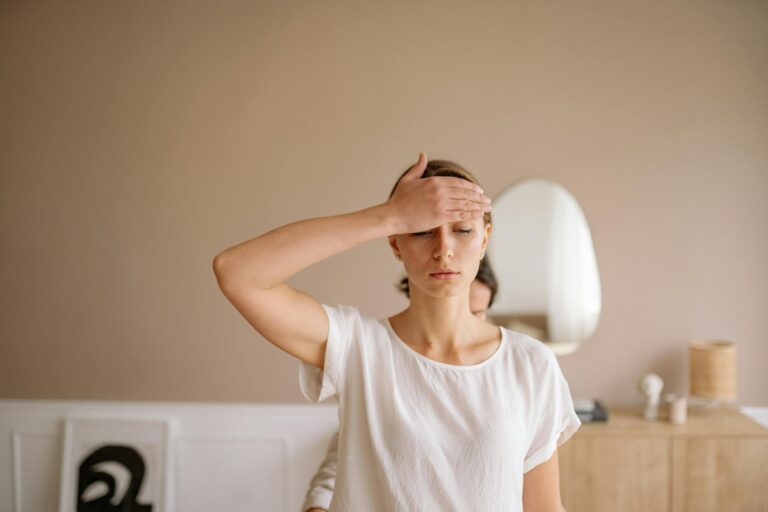 Woman practicing mindfulness meditation with hand on forehead indoors.